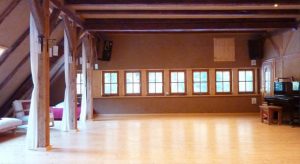 Ein Raum mit Lehmputz, Holzboden, Fensterfront und einem Klavier