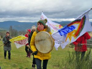 Frauen gehen mit bemalten Fahnen durch die Natur