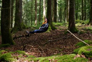 Eine reife Frau entspannt an einem Baum mitten im Wald