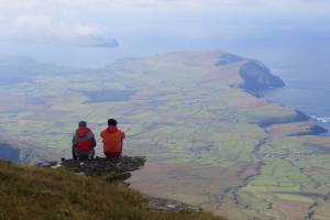 Zwei Teilnehmer sitzen auf einem Stein und betrachten die Aussicht auf den irischen Atlantik