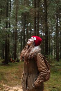 Picture of pretty young woman standing in the forest. Looking aside.