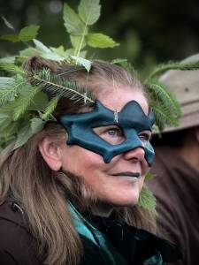 Eine Teilnehmerin mit Maske und grünen Zweigen im Haar