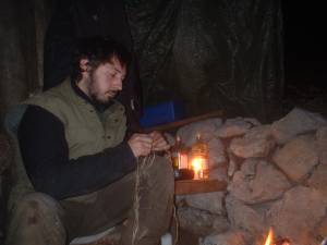 Andre Lorino dreht brenneselschnur am Lagerfeuer